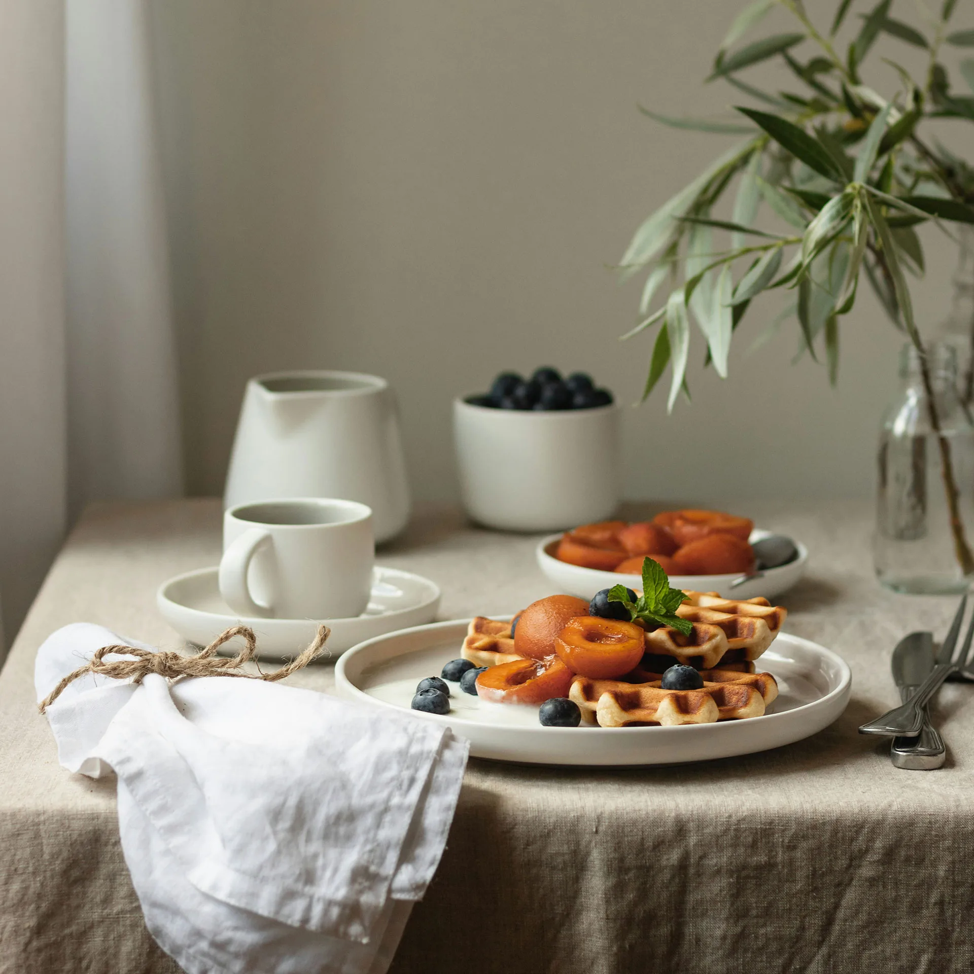 Dukat bord med ljus duk, kaffe och frukost